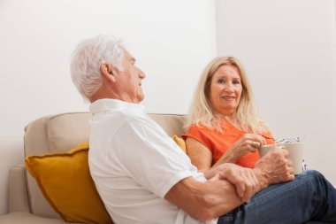 Mutlu çift çay içiyor, kanepede oturuyor.