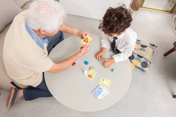 Boy playing board game with his grandfather