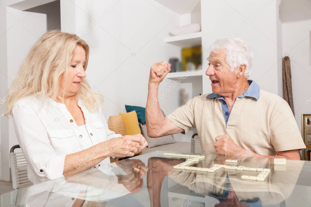 Happy senior couple playing game Dominoes