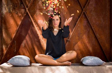 Bahçede yoga yapan genç bir kadın. İç huzuru bulmak. Pozitif enerji. Özgürlük için. Rahatlama. Meditasyon. Kız bacak bacak üstüne atmış, tomurcuk yapraklarıyla oturuyor.