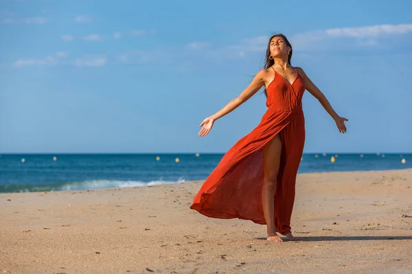 穿着红衣服赤脚站在沙滩上的年轻漂亮的女人 在海上享受自由的快乐女孩 — 图库照片