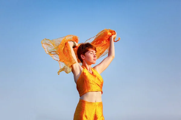 FREEDOM, MOVEMENTS, WOMAN ON A GATEWAY WITH A ORANGE SCARF