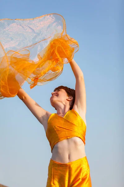 FREEDOM, MOVEMENTS, WOMAN ON A GATEWAY WITH A ORANGE SCARF