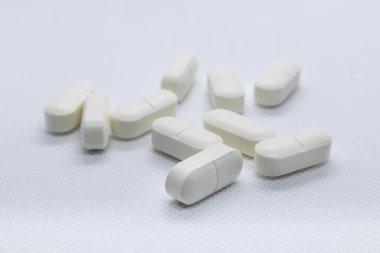 Beyaz arka planda beyaz uzun haplar. İlaç ilacı hafif renkler makro izole yakın çekim