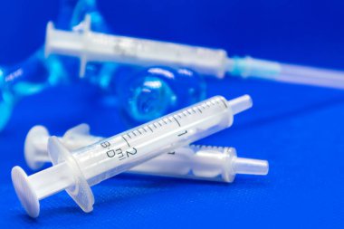 Mavi canlı yüzeyde beyaz 2 ml 'lik şırıngalar. İğne, aşı, tedavi için tıbbi araç