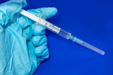 Beyaz 2 ml 'lik şırınga makrosu elinde mavi lastik eldiven ve parlak mavi. Tıbbi araç, enjeksiyon, aşı, tedavi