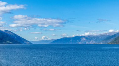 Norveç 'in kuzeyindeki açık mavi, canlı, soğuk deniz manzarası. Güneşli mavimsi doğa manzarası, uzak Sognefjord dağları