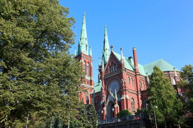 Finlandiya Helsinki 'deki ünlü gotik kırmızı kilise tarihi mimarisi mavi gökyüzü ve canlı yeşil çimlerle. Şehir Avrupa seyahat fotoğrafçılığı
