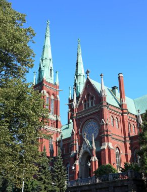 Finlandiya Helsinki 'deki ünlü gotik kırmızı kilise tarihi mimarisi mavi gökyüzü ve canlı yeşil çimlerle. Şehir Avrupa seyahat fotoğrafçılığı