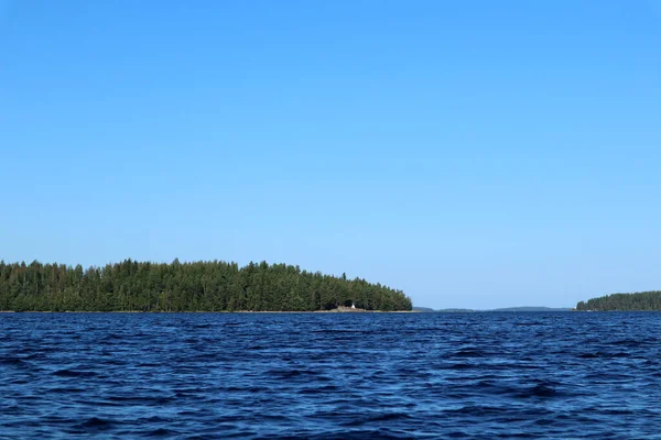 青い水の澄んだ空の晴れた日に湖の水の波を閉じます 深い色の水で自然のスカイラインや森の美しさ ボートからの写真 — ストック写真