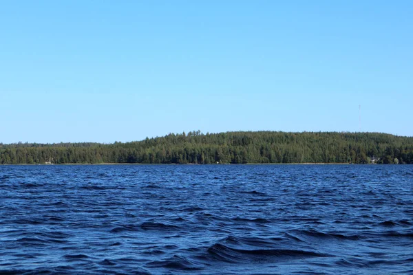 青い水の澄んだ空の晴れた日に湖の水の波を閉じます 深い色の水で自然のスカイラインや森の美しさ ボートからの写真 — ストック写真