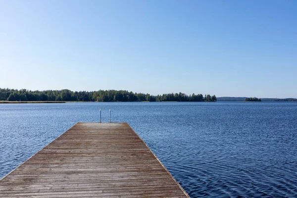 自然の中で穏やかな青い湖の晴れた日に金属はしごを持つ木製のスイミングドック桟橋フィンランド牧歌的な自然リゾート — ストック写真