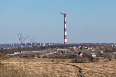 Kırmızı beyaz çizgili enerji ısı santrali borusu. Avrupa, Ukrayna kırsal kesimi, temiz gökyüzü manzarası hava kirliliği duman kulesi.