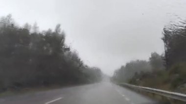 Şiddetli yağmur fırtınasının içinden geçen dramatik kuzey İskandinav rotası. Arabanın ön camına yağmur damlaları düşer. İsveç 'in kuzeyindeki Avrupa otobanına git. Doğa ormanı, yol manzarası