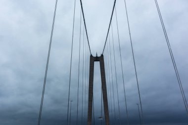 Kara dramatik gökyüzündeki köprü kemeri ağır kara bulutları ortaya çıkarıyor. İsveç otoban kuzey mimarisi