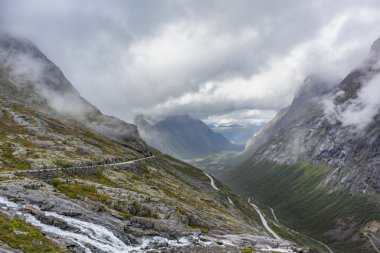 Ünlü Norveç dağları vadi manzaralı Trollstigen yolu. Kayalar, şelaleler, dramatik bulutlar, turizm, Avrupa seyahati