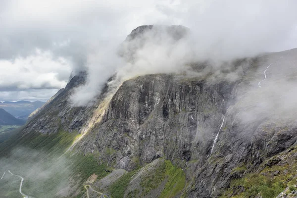 挪威欧洲巨石阵山路上有瀑布和云彩从岩石山中落下的山脉景观 — 图库照片
