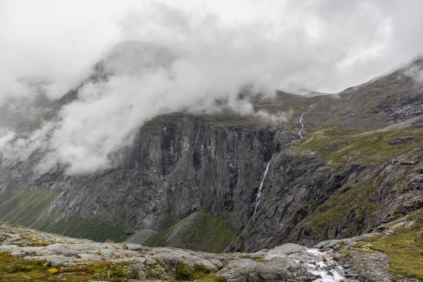 挪威欧洲巨石阵山路上有瀑布和云彩从岩石山中落下的山脉景观 — 图库照片