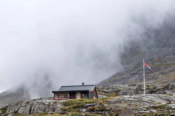 Traditional norwegian wooden mountain huts cabin at Troll path Trollstigen, Norway. Cloudy white sky and rocky hills travel scenery.