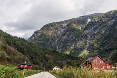 İskandinavya doğa yolculuğunda dağlar bulutlu bir yoldur. Sisli bulutlu gökyüzü ile kayalıklara ve orman tepelerine bakın. Kuzey manzarası sürüş yolu arka plan.