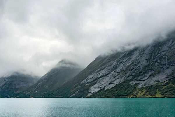 冷たい色ノルウェーフィヨルド冷たい水で風光明媚な霧の重い雲の風景 北部の夏の北欧で劇的なパノラマビュー 北への旅行 — ストック写真