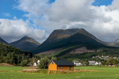 Norveç kırsal alanı, bulutlu tepeler doğa yolculuğu. Orman tepeleri, yeşil tarlalar ve ahşap evler. Kuzey peyzaj sürücüsü geçmişi.