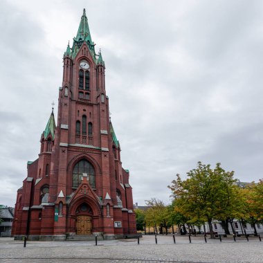 Norveç 'in Bergen kentindeki yüksek St. John Kilisesi' nin (Johanneskirken) panoramik manzarası. Kırmızı tuğla ve bakır detaylarla Gotik-diriliş kilisesi. Bulutlu sonbahar günü şehir turizmi