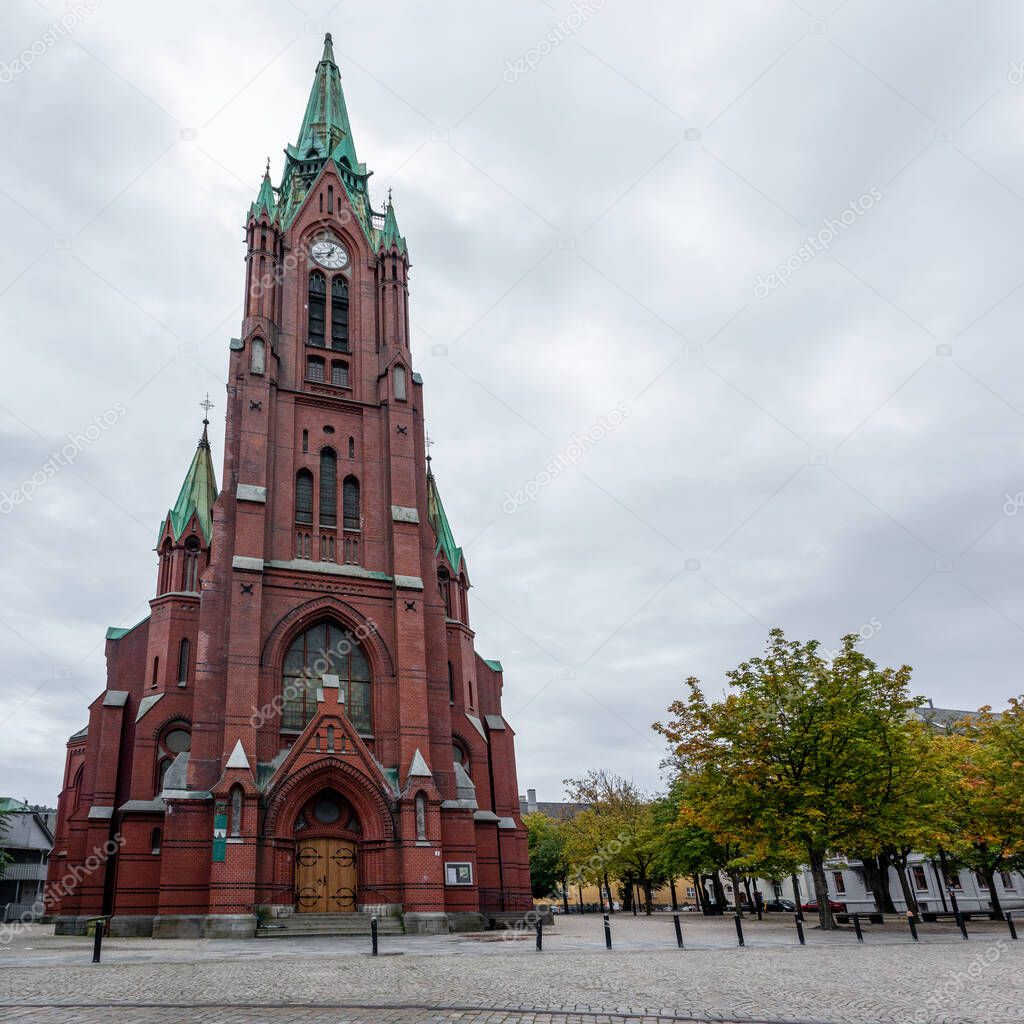 Panoramic view of high St. John's Church (Johanneskirken) in Bergen, Norway. Gothic-revival church with red brick & copper details. Cloudy autumn day city tourism