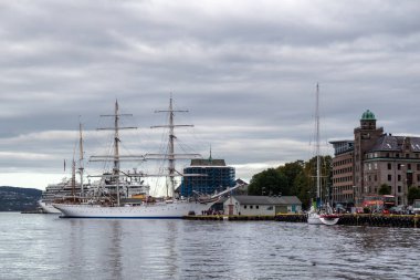 Bergen, Norveç - 09 Eylül 2019: Bryggen rıhtımındaki tarihi binaların yakınında güzel yansıması olan büyük beyaz yelkenli gemi rıhtımda.