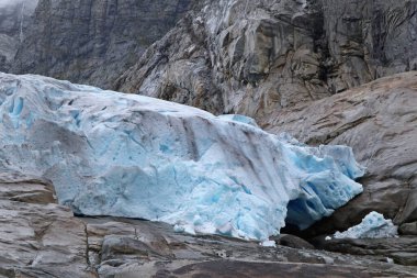 Jostedalsbreen Ulusal Parkı 'ndaki Nigardsbreen' e bulutlu bir gezi. Norveç dağlarının manzarası mavi buz, kaya, buzullar, kar. İklim değişikliği, eriyen buzullar