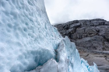 Nigardsbreen buzulu ve kar Jostedalsbreen Ulusal Parkı 'na yakın. Norveç dağlarının manzarası koyu mavi buz, kayalar ve karla kaplı. İklim değişikliği, eriyen buzullar