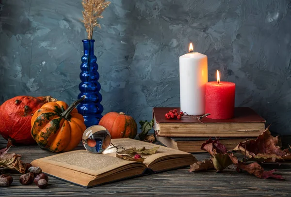 Witch\'s room. Autumn still life with pumpkins, candles, old books ,autumn leaves, crystal ball