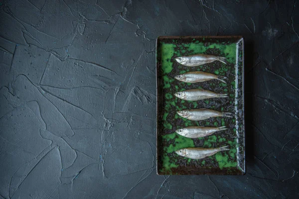 Small salted fish of Baltic herring, sprats on a black background. Top view. Concept — Stock Image Small salted fish of Baltic herring, sprats on a black background. Top view. Concept Royalty Free Stock Photos