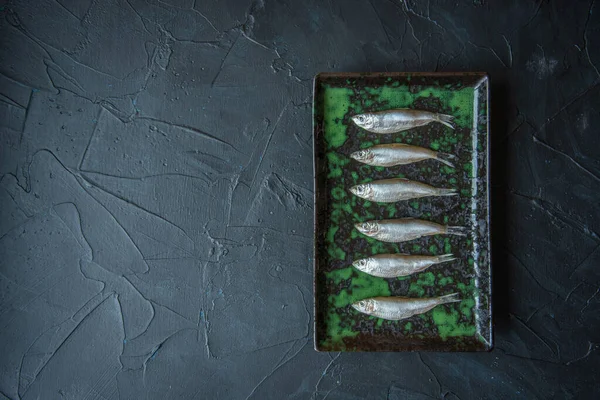Small salted fish of Baltic herring, sprats on a black background. Top view. Concept — Stock Image Small salted fish of Baltic herring, sprats on a black background. Top view. Concept Stock Picture