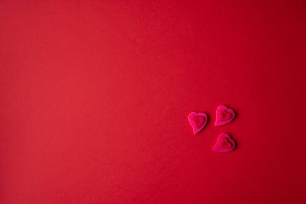 Three small pink hearts on a red background. Copy space