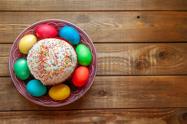 Easter. Colored eggs and Easter cake on a wooden background.