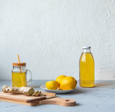 Şişe içinde kombu çayı, limon, arka planda dilimlenmiş zencefil.