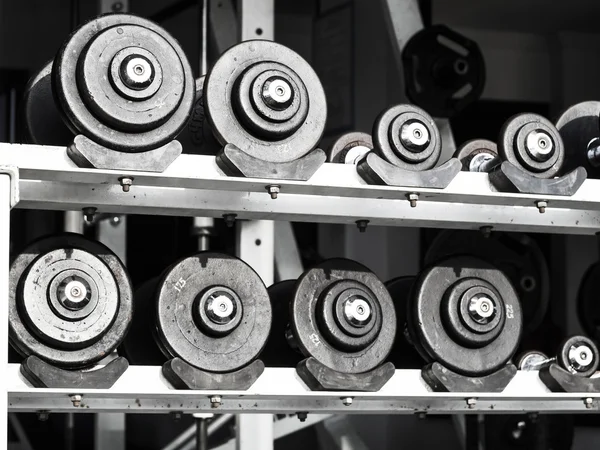 Muchos pesos de hierro en la estantería en blanco y negro —  Fotos de Stock