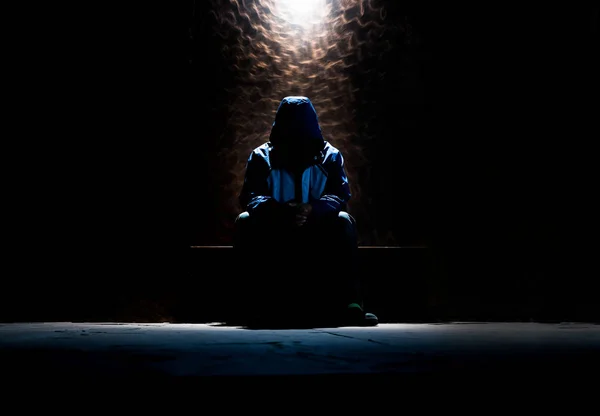 Hombre irreconocible esperando en la habitación oscura con luz única tan — Foto de Stock