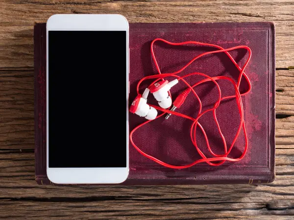 Teléfono inteligente y orejas enchufe en fondo de madera —  Fotos de Stock