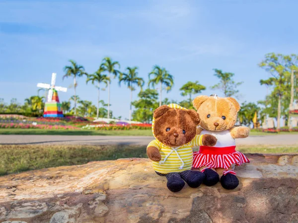 couple of teddy bear toys standing outdoor in the park