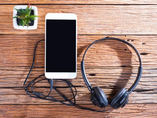 Smart phone and ears plug on wooden background — Stock Photo, Image