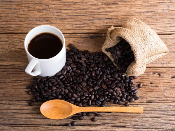 Black roasted coffee beans on aged wood — Stock Photo, Image