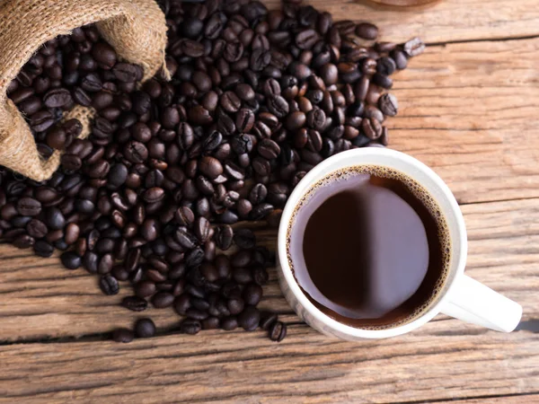 Black roasted coffee beans on aged wood — Stock Photo, Image