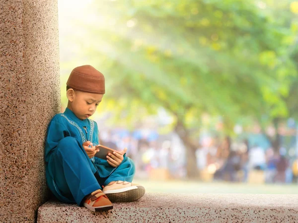 Glückliches muslimisches Kind mit vollem Kleid spielt Smartphone — Stockfoto