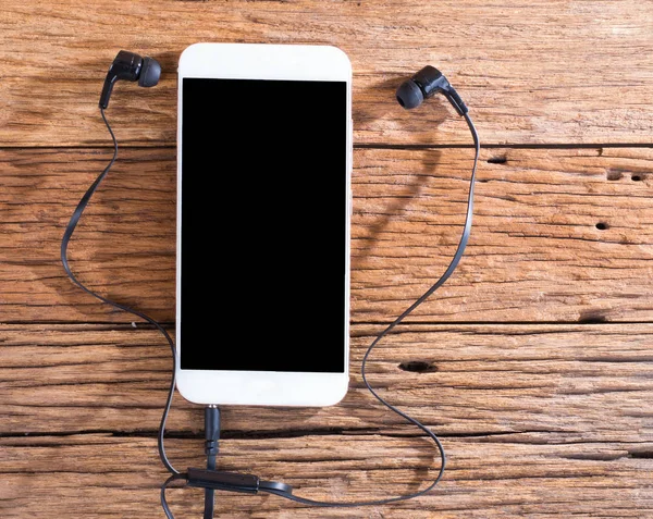 Smart phone and ears plug on wooden background — Stock Photo, Image