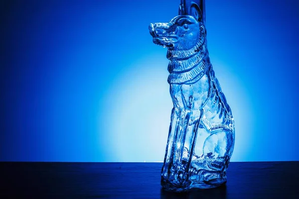 Background with a glass bottle in the shape of a dog, backlit.