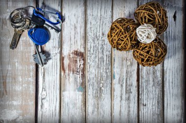 Arka planda bir sürü anahtar ve ahşap yüzeyde rattan toplar var.