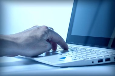 Dizüstü bilgisayar klavyesinde çalışan bir iş adamının el yazısı. Arka ışık. İş konsepti