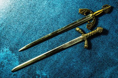 Koyu mavi arka planda paralel duran iki şövalye kılıcı. Yukarıdan görüntüle